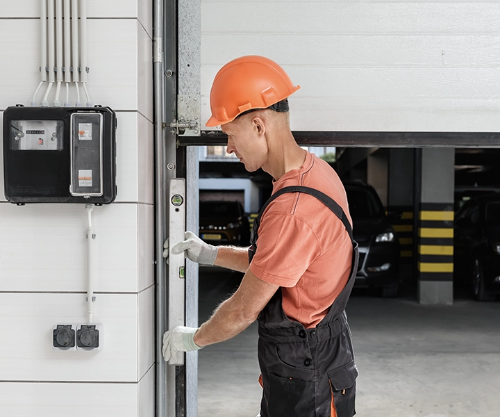 Technicien réglant une porte de garage automatique lors d’une intervention de réparation au Luxembourg