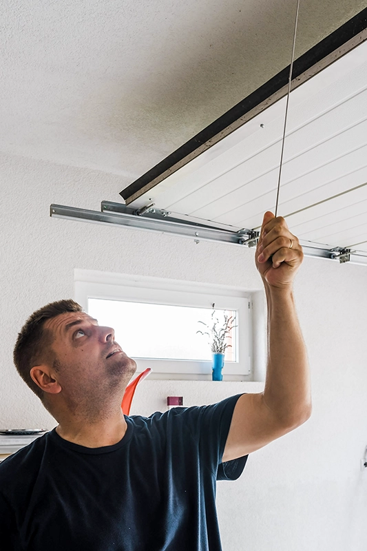 Technicien testant une porte de garage motorisée en panne dans une habitation au Luxembourg – dépannage moteur porte de garage